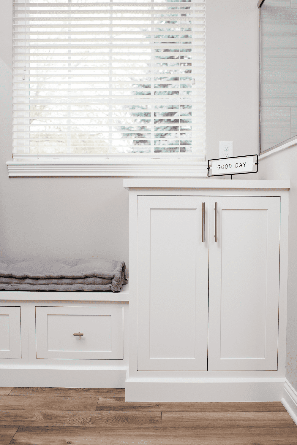 Nicholas Design Build | A refreshing bathroom remodel featuring a white color scheme, complete with a comfortable bench and an ample window that fills the space with natural light.