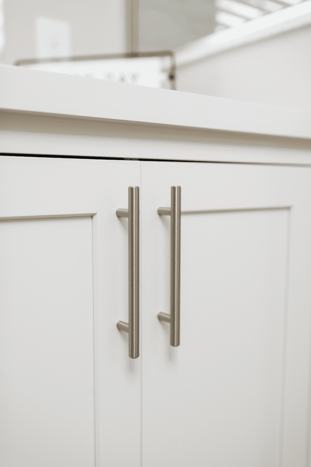 Nicholas Design Build | A close up of a white cabinet with metal handles for a bathroom remodel.