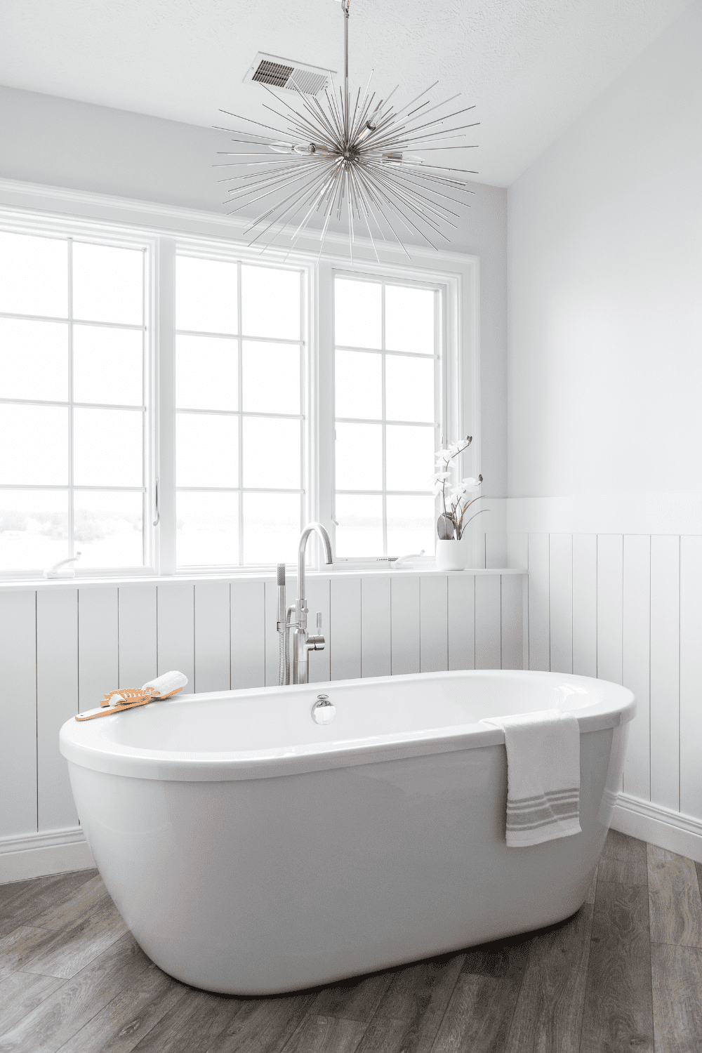 Nicholas Design Build | A white bathtub in a master bathroom with wood floors.