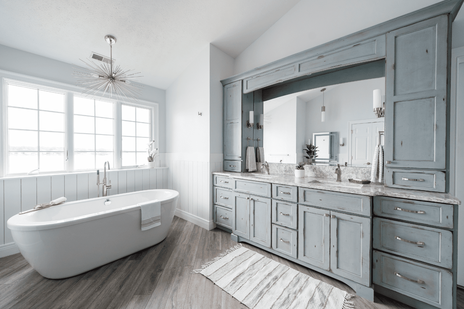 Nicholas Design Build | Master bathroom remodel with blue cabinets and a tub.