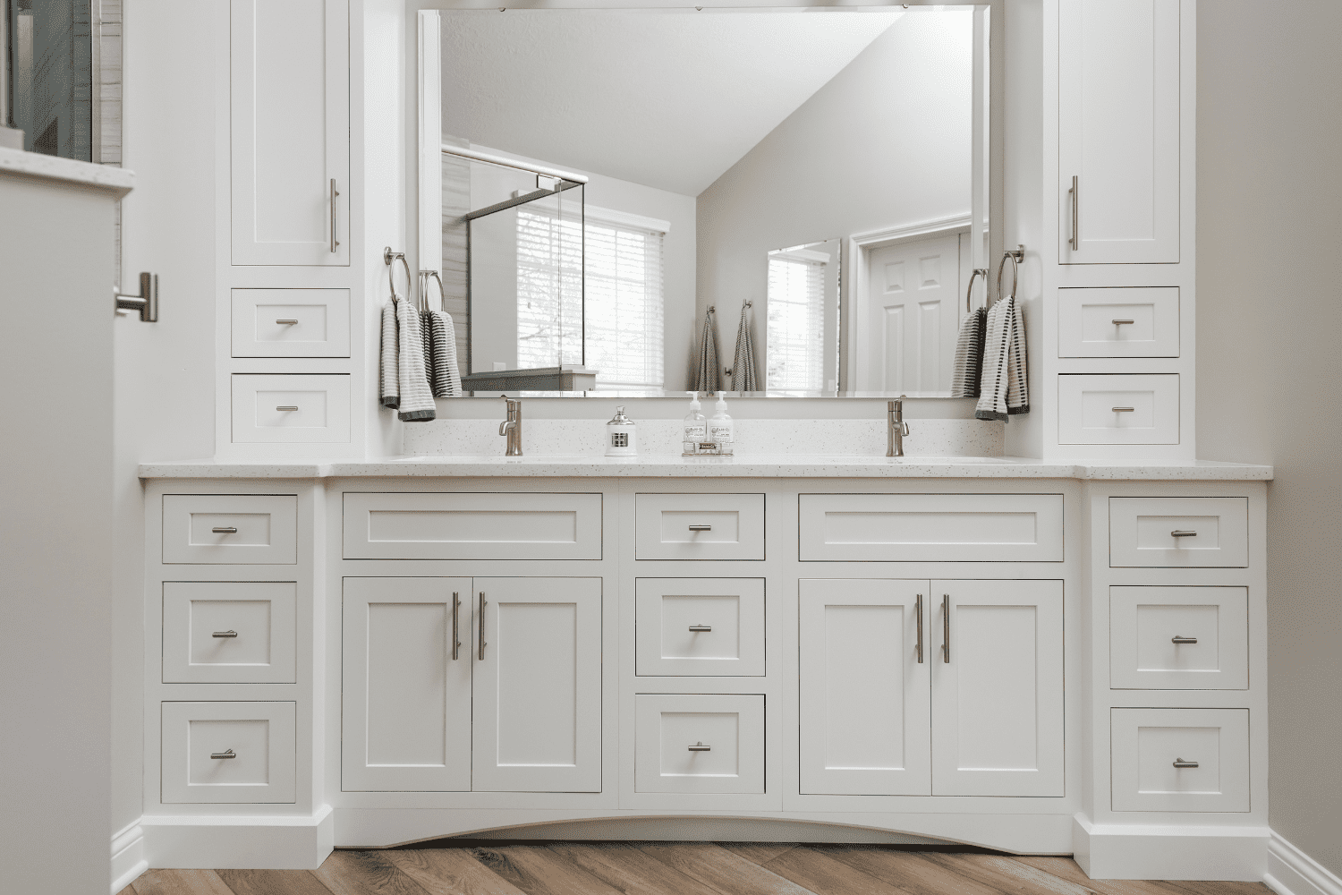 Nicholas Design Build | A bathroom remodel with white cabinets and a large mirror.