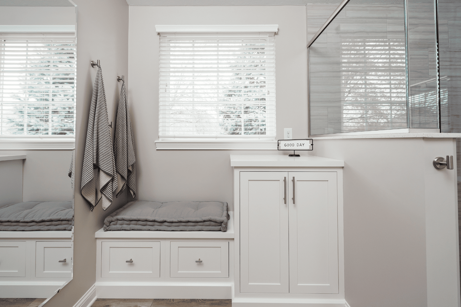 Nicholas Design Build | A bathroom remodel featuring a white bathroom with a bench and a window.