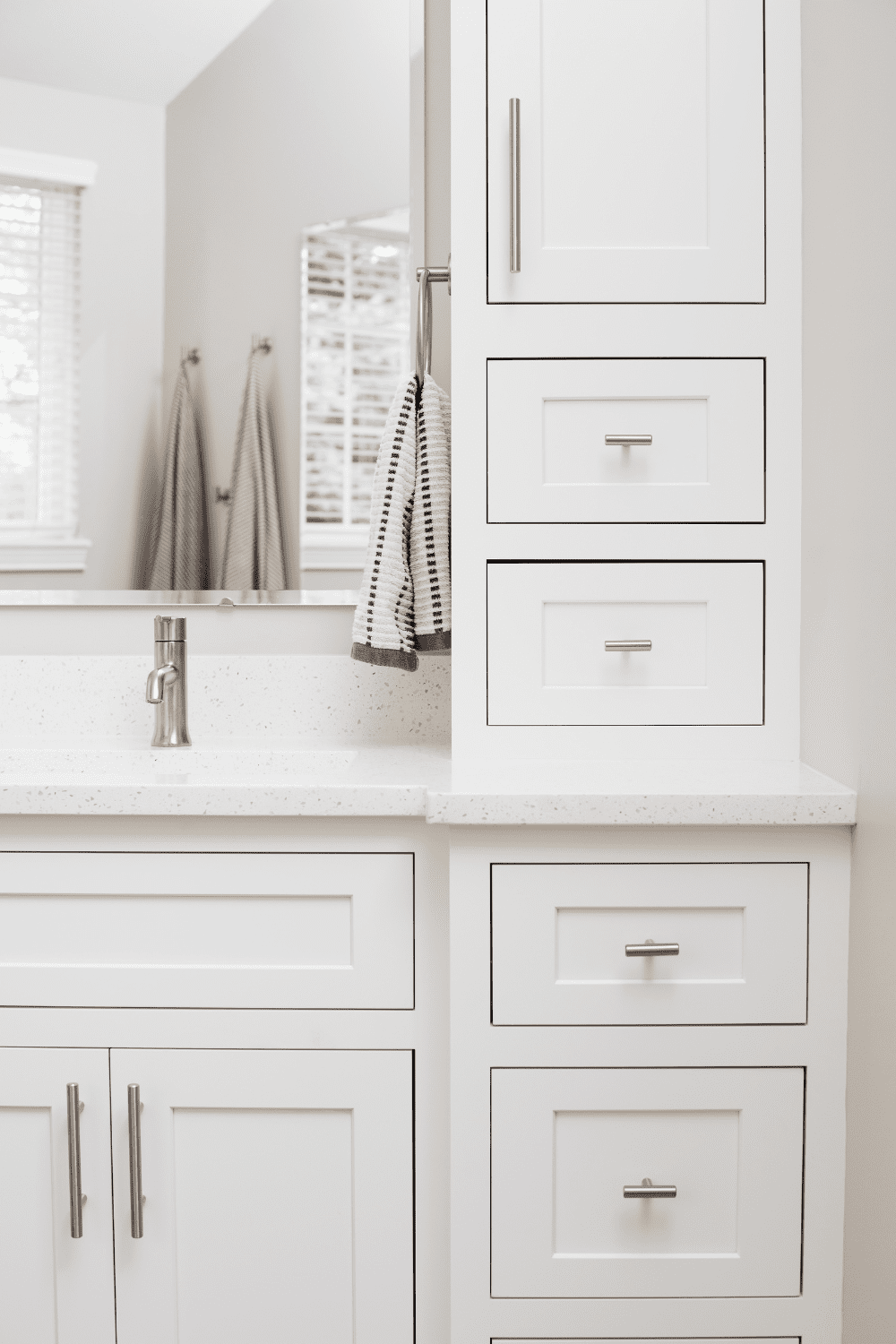 Nicholas Design Build | A renovated bathroom with white cabinets and a mirror.