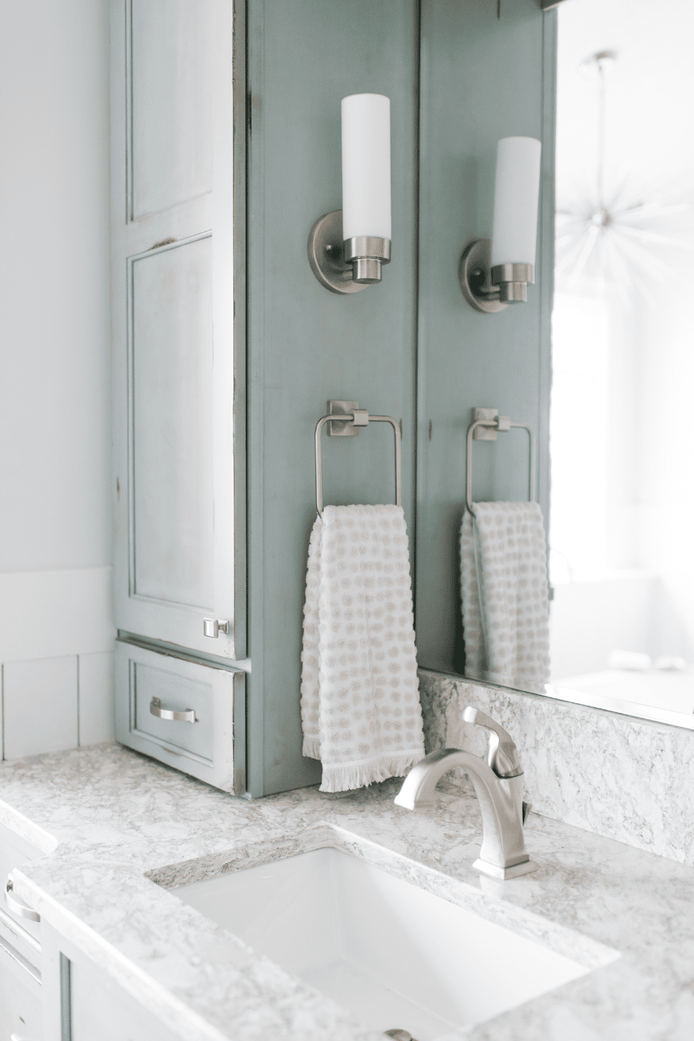 Nicholas Design Build | A master bathroom remodel with blue cabinets and a mirror.