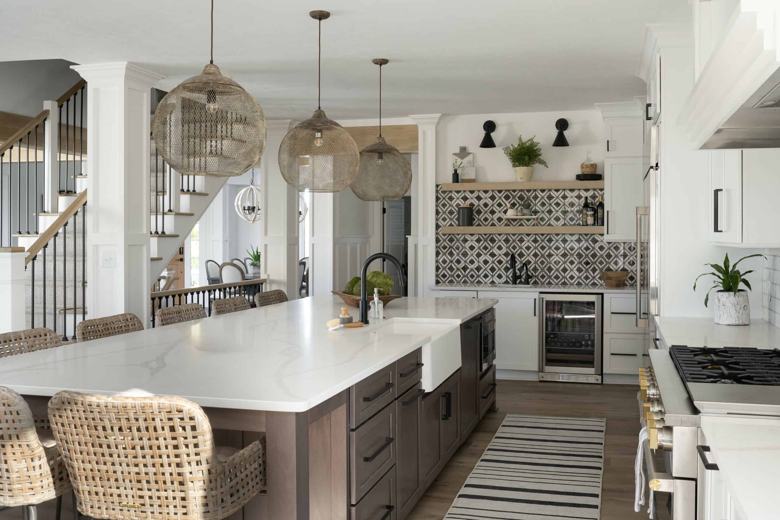 Boho style kitchen with wicker pendant lights, wicker barstools at large center island, farmhouse sink, and mini bar.