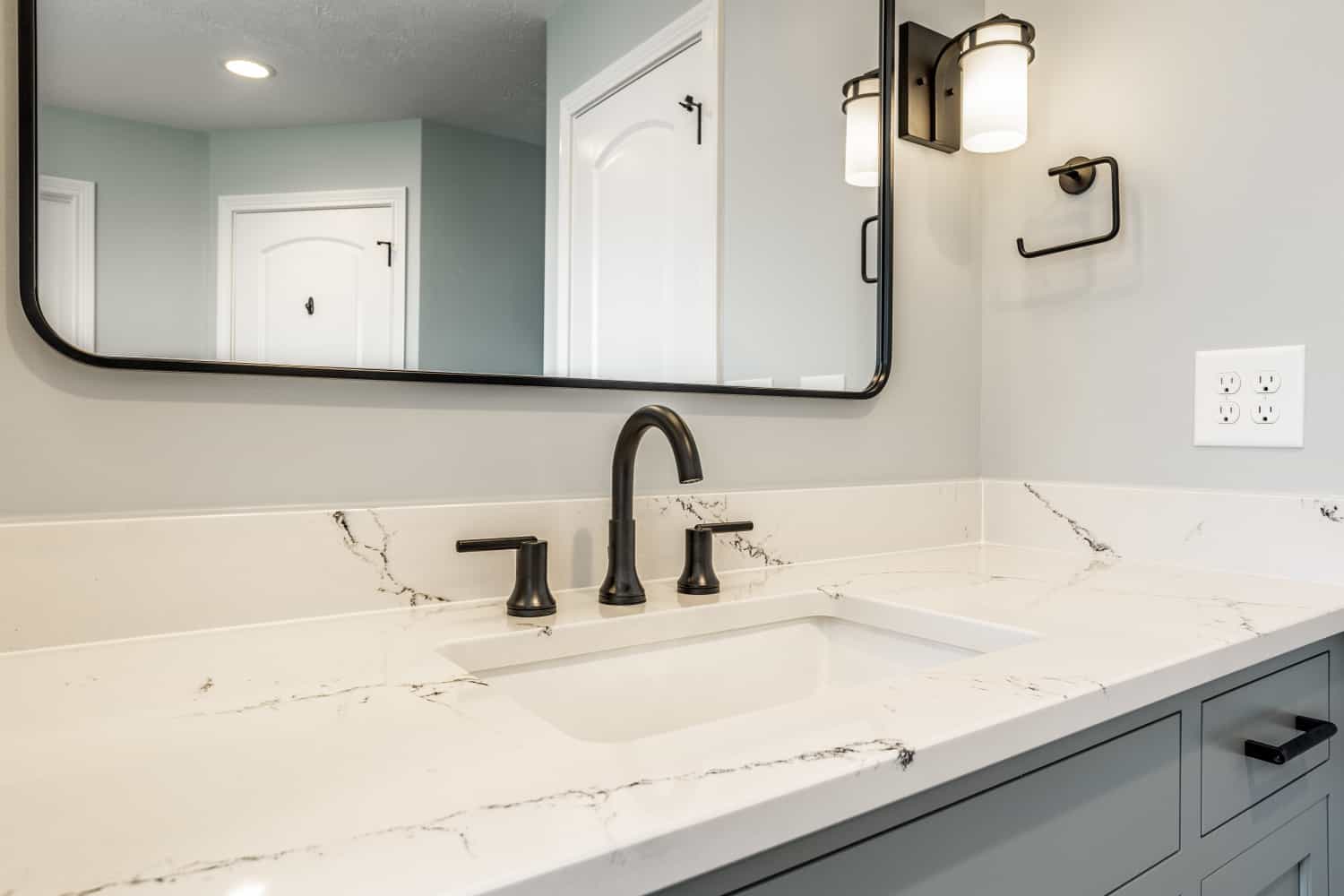 Nicholas Design Build | A black and blue bathroom with marble counter tops and a mirror.
