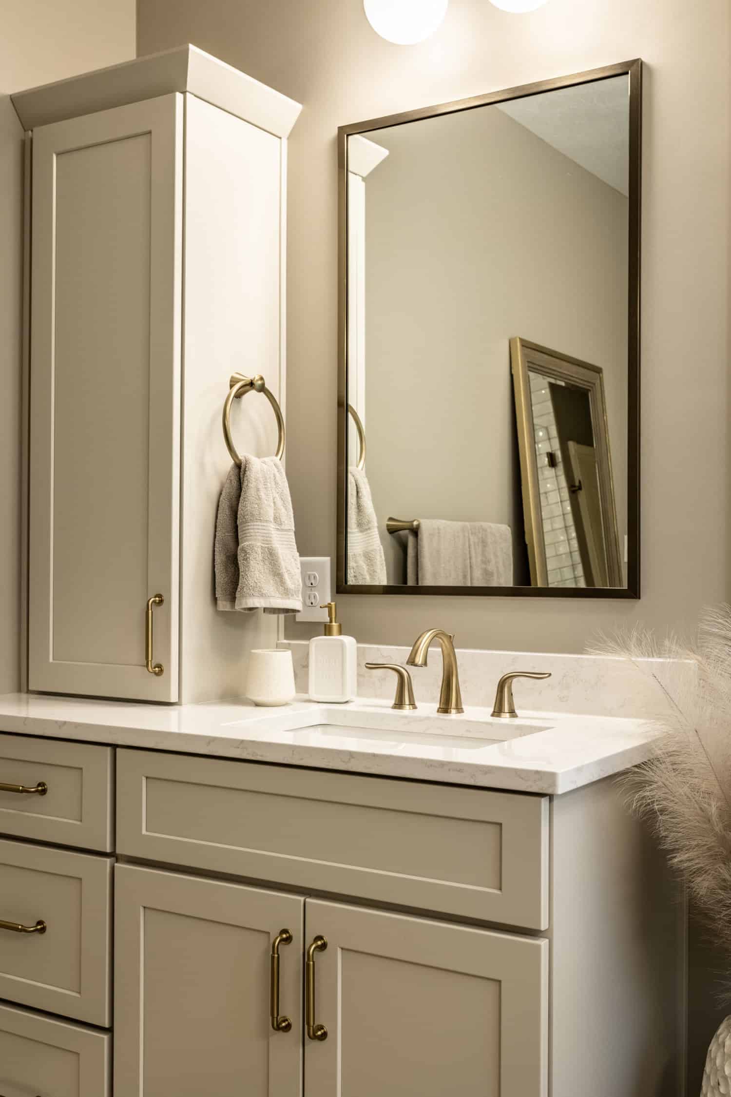 Nicholas Design Build | A modern bathroom with white cabinets and a brushed gold mirror.