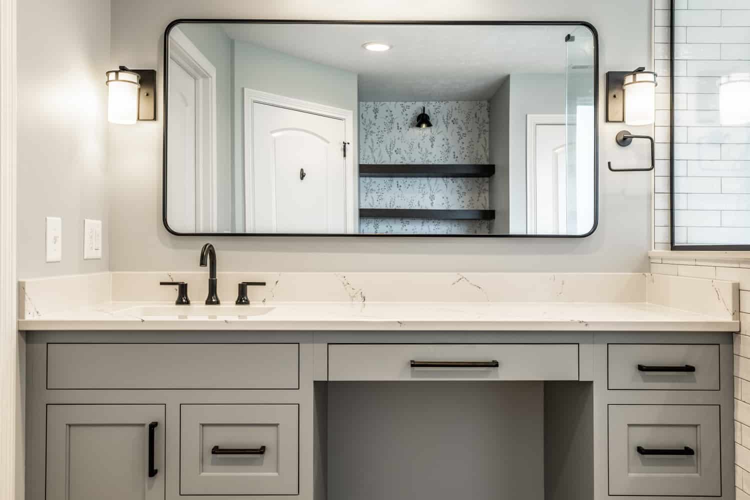 Nicholas Design Build | A bathroom with a gray vanity and mirror in a black and blue color scheme.