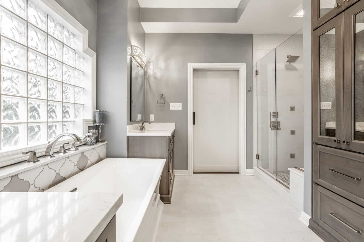 Nicholas Design Build | A barn door bathroom with gray walls and a white tub.