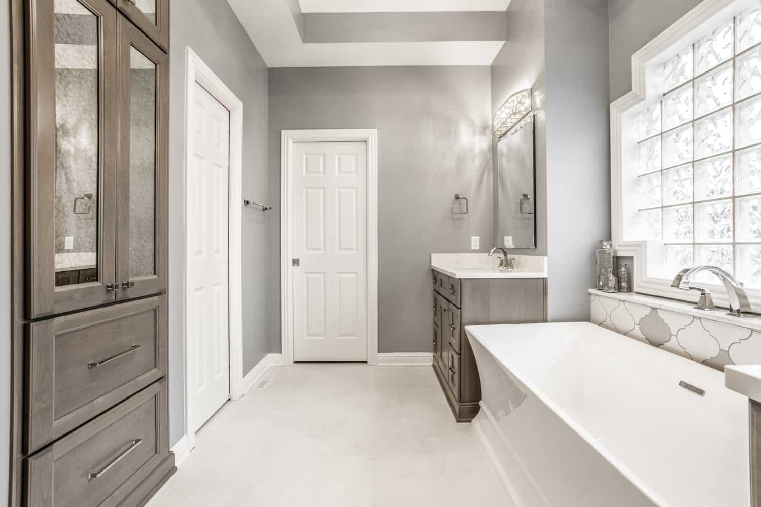 Nicholas Design Build | A bathroom with a tub and sink featuring a white and gray color scheme.
