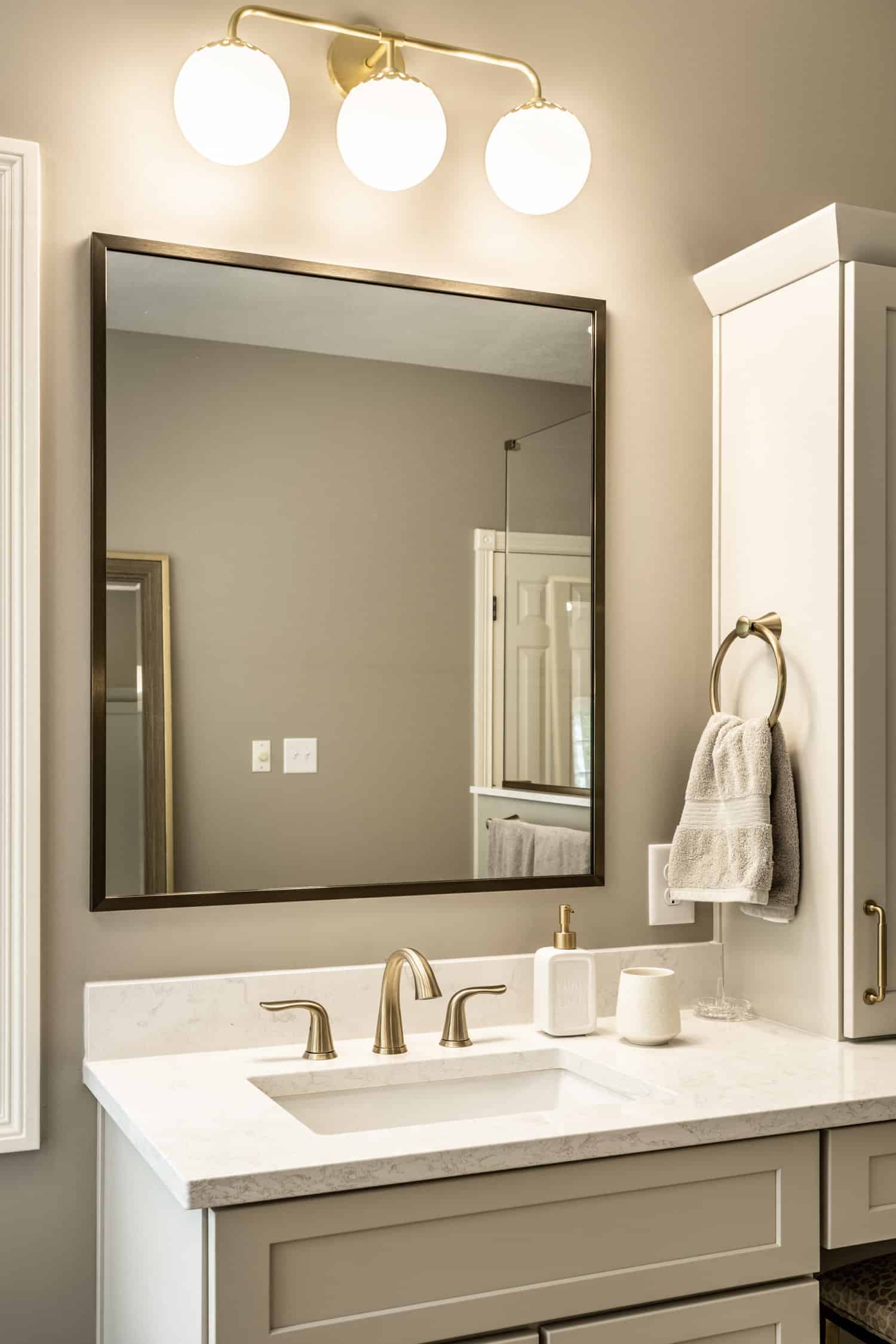 Nicholas Design Build | A modern bathroom with two sinks and a brushed gold mirror.