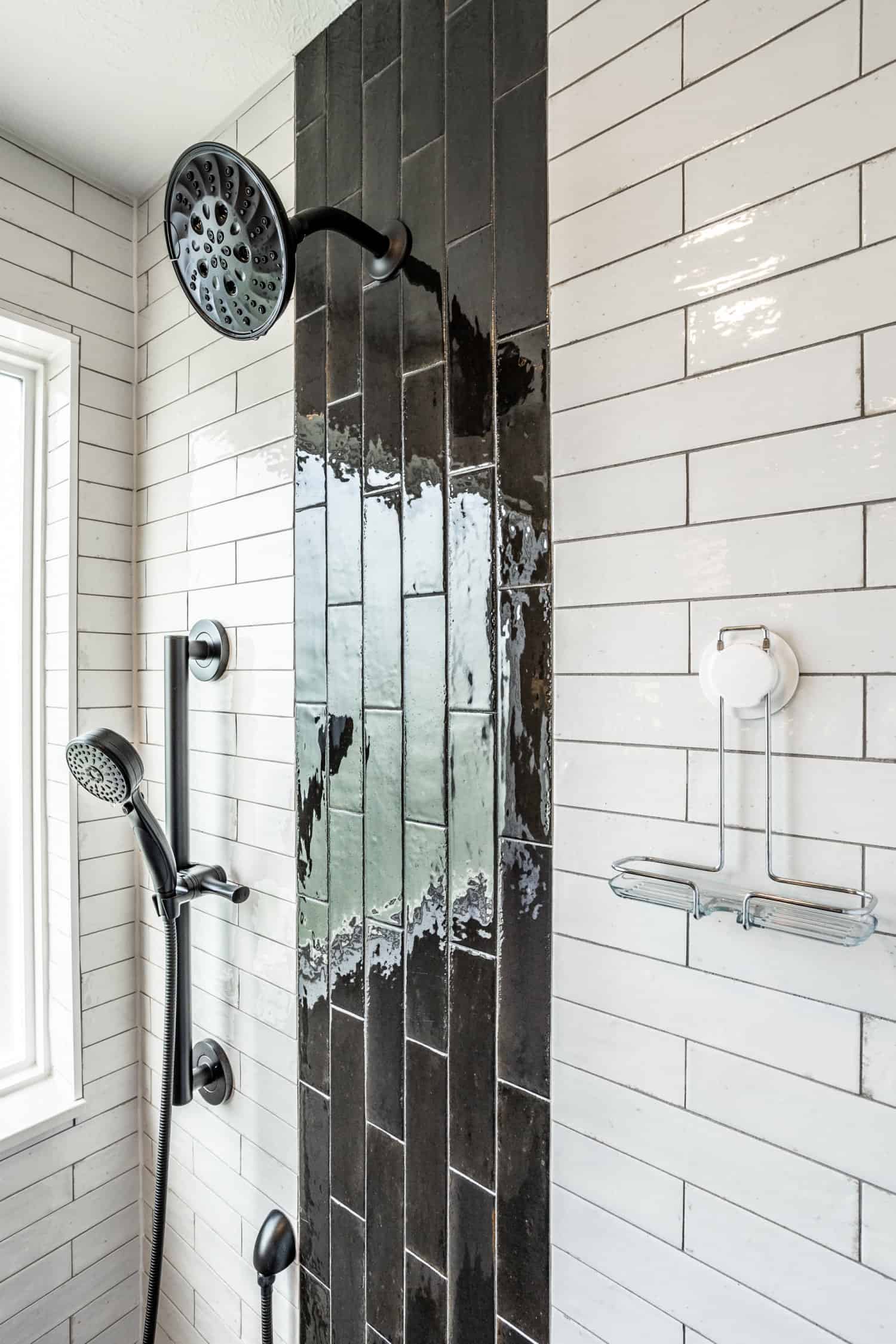 Nicholas Design Build | A black and white tiled shower with a handheld shower head in a black and blue bathroom.