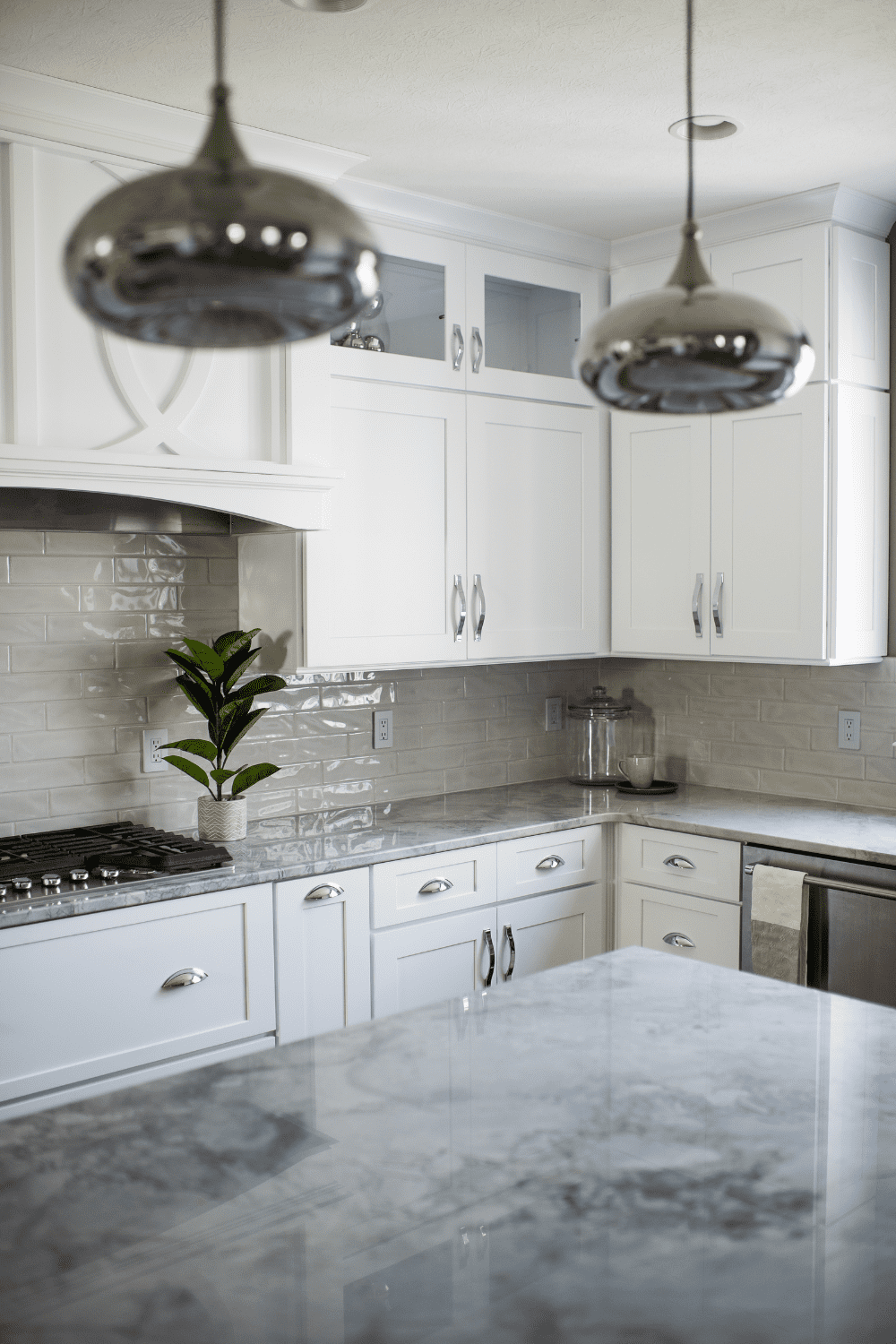 Nicholas Design Build | A kitchen with white cabinets and marble counter tops.