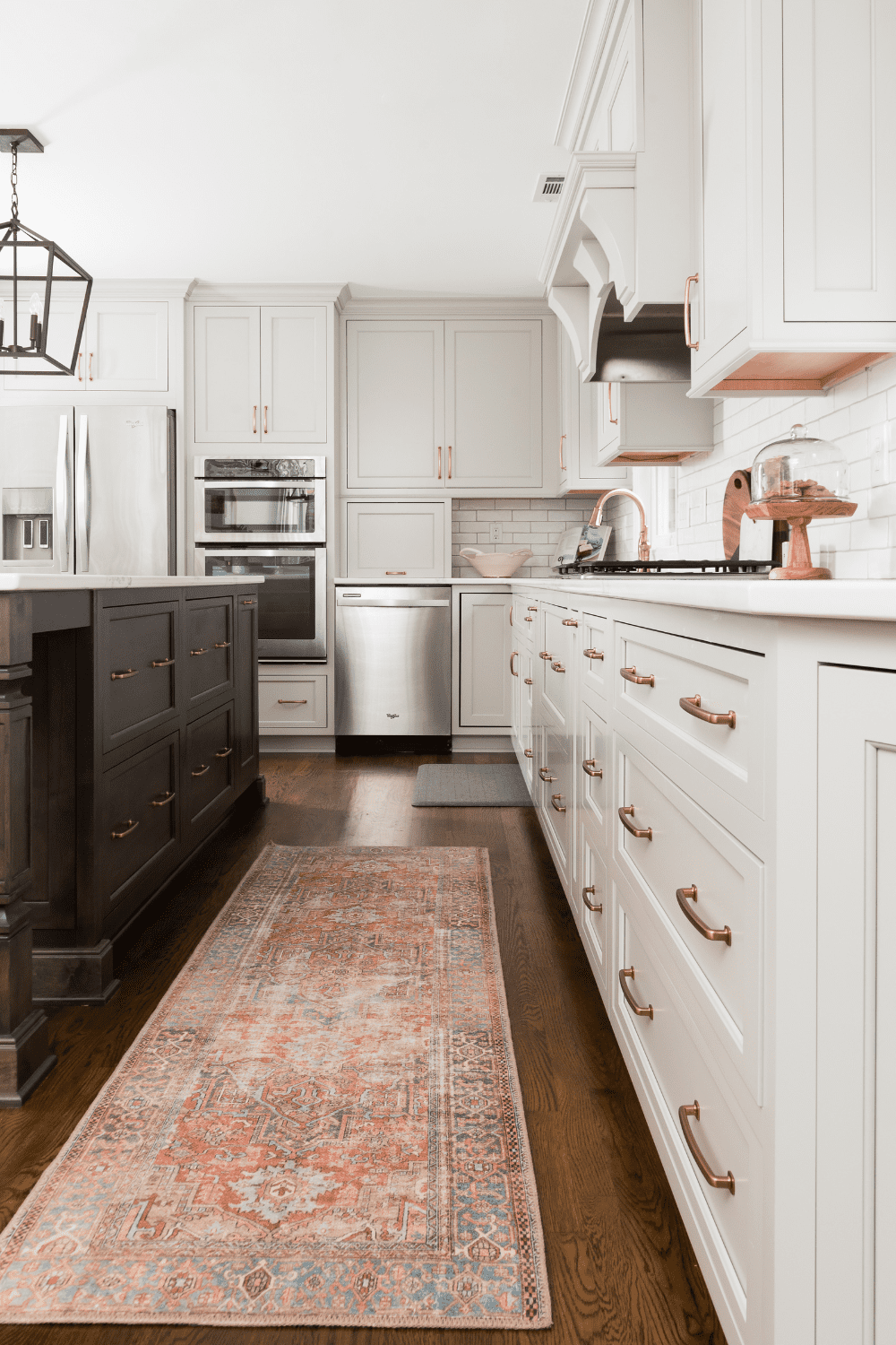 Nicholas Design Build | A kitchen with white cabinets and a rug.