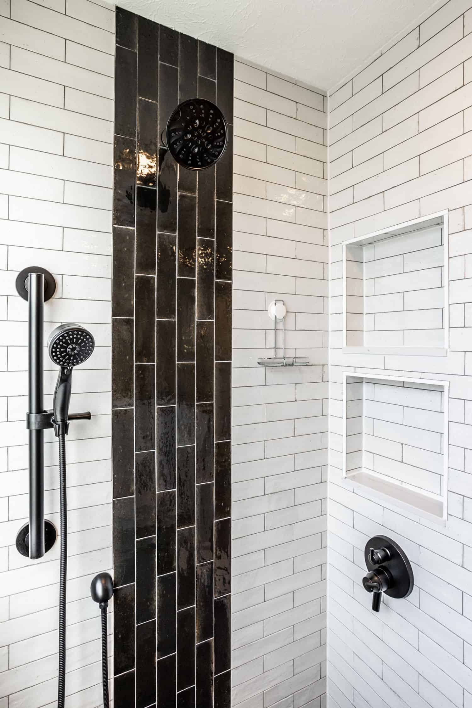 Nicholas Design Build | A black and white tiled shower with a hand shower in a blue bathroom.