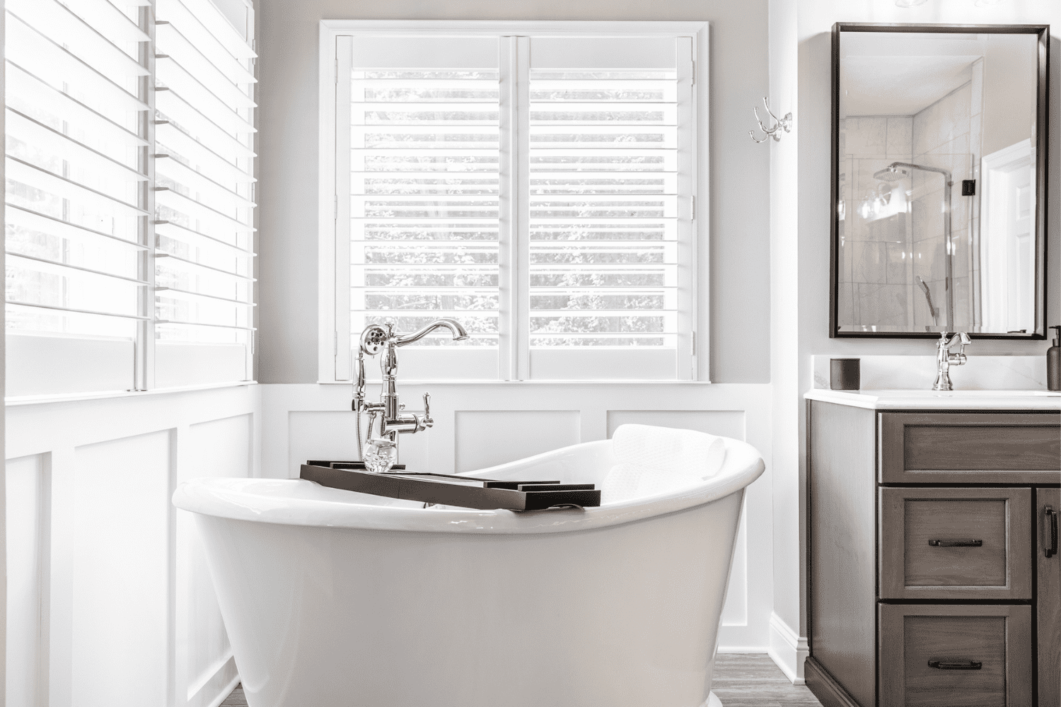 Nicholas Design Build | A master bath remodel with a white tub and wooden shutters.