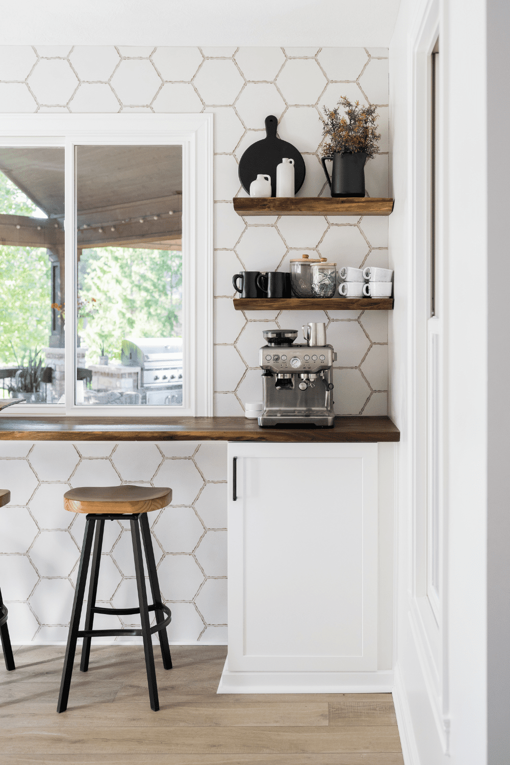 Nicholas Design Build | A white kitchen with stools and a window.