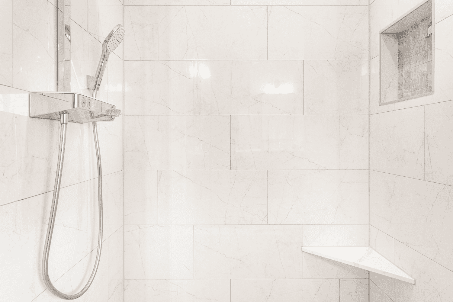 Nicholas Design Build | A white tiled shower with a handheld shower head in a master bath remodel.