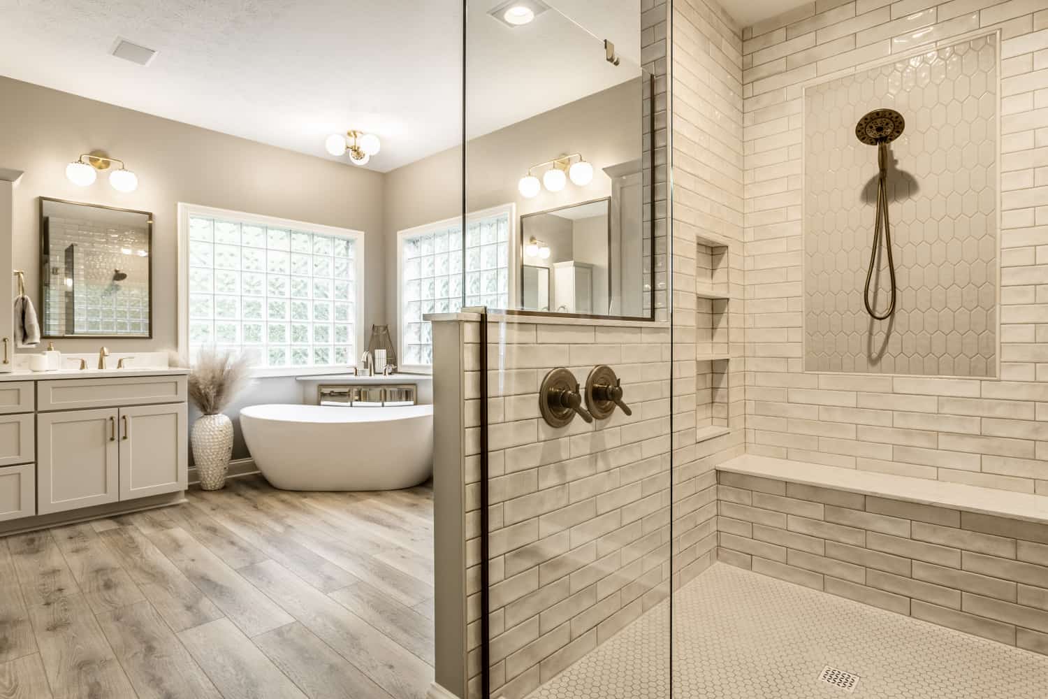 Nicholas Design Build | A modern white bathroom with a walk-in shower featuring brushed gold accents.