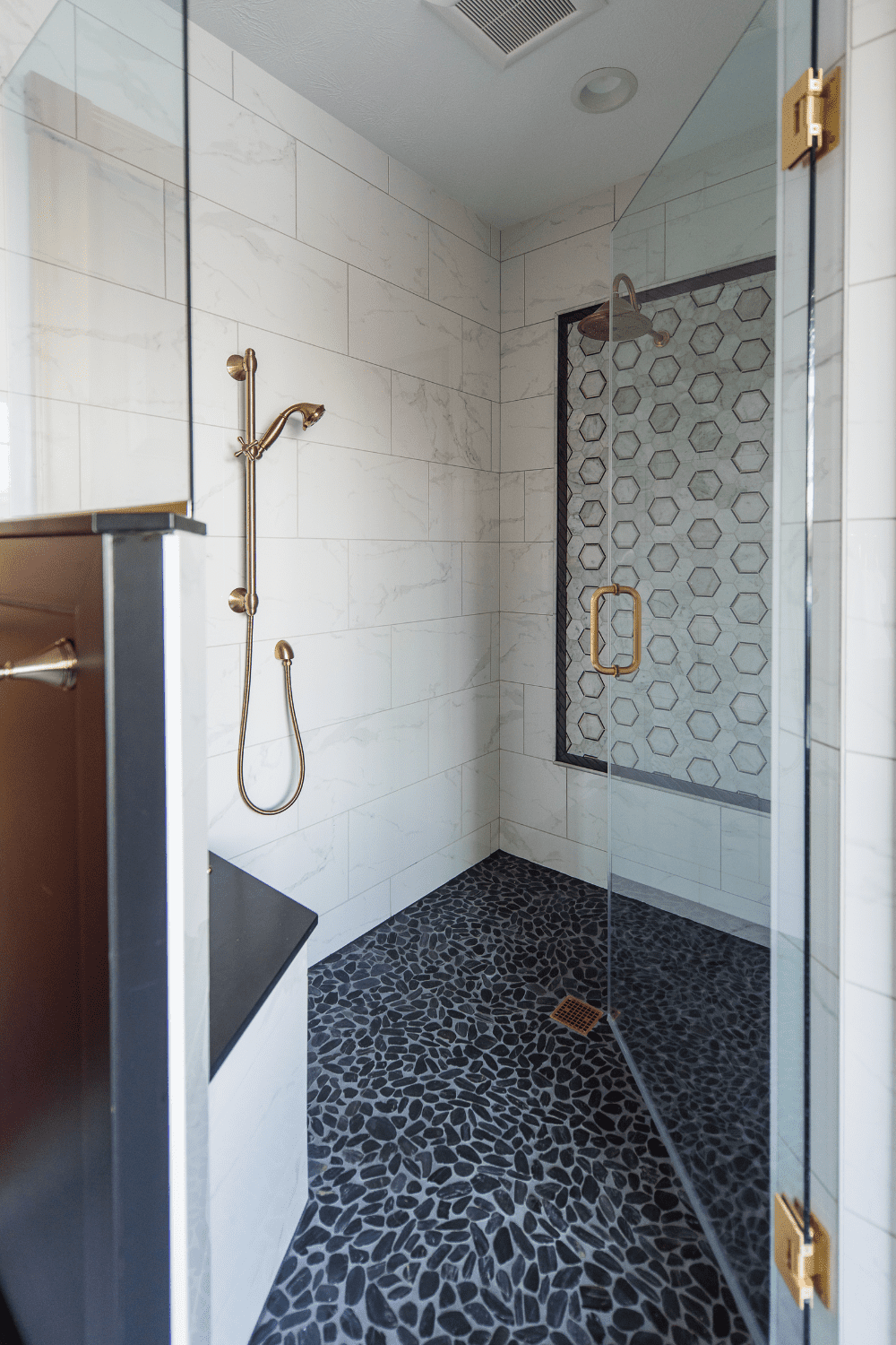 Nicholas Design Build | A black and white tiled shower with a glass door.