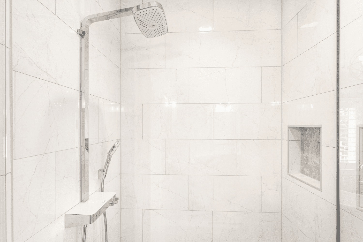 Nicholas Design Build | Master bath remodel with a white tiled shower featuring a shower head.