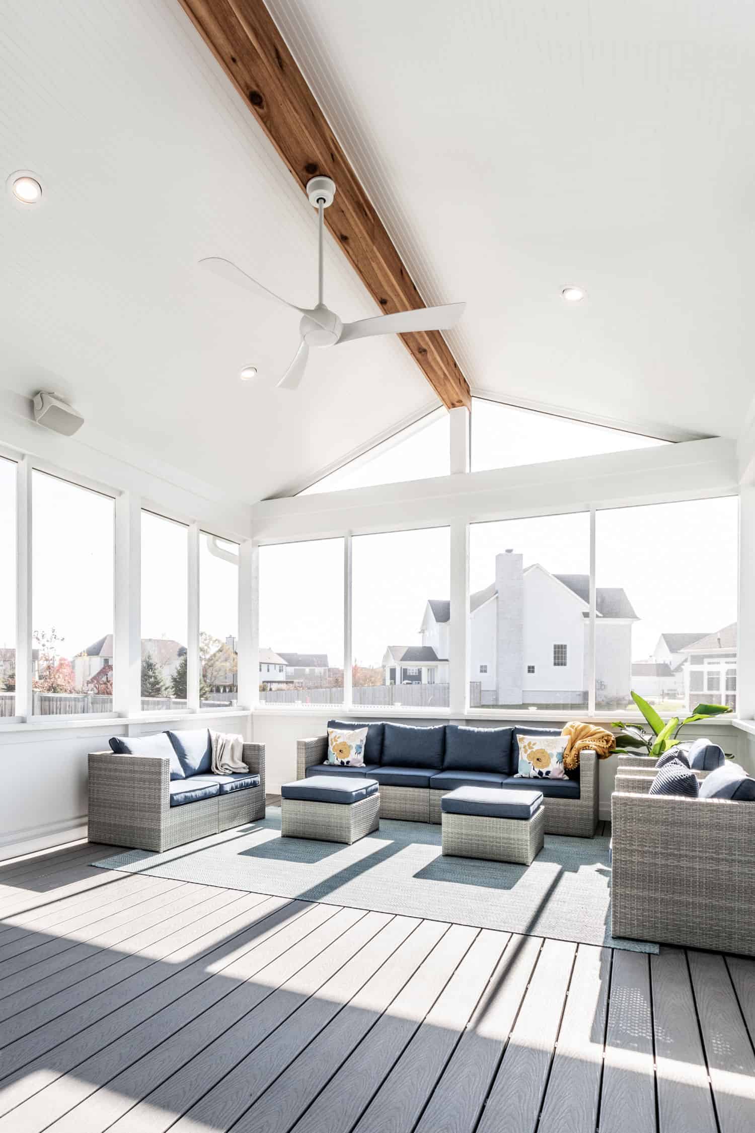 Nicholas Design Build | A remodeled screened-in porch with couches and a ceiling fan.