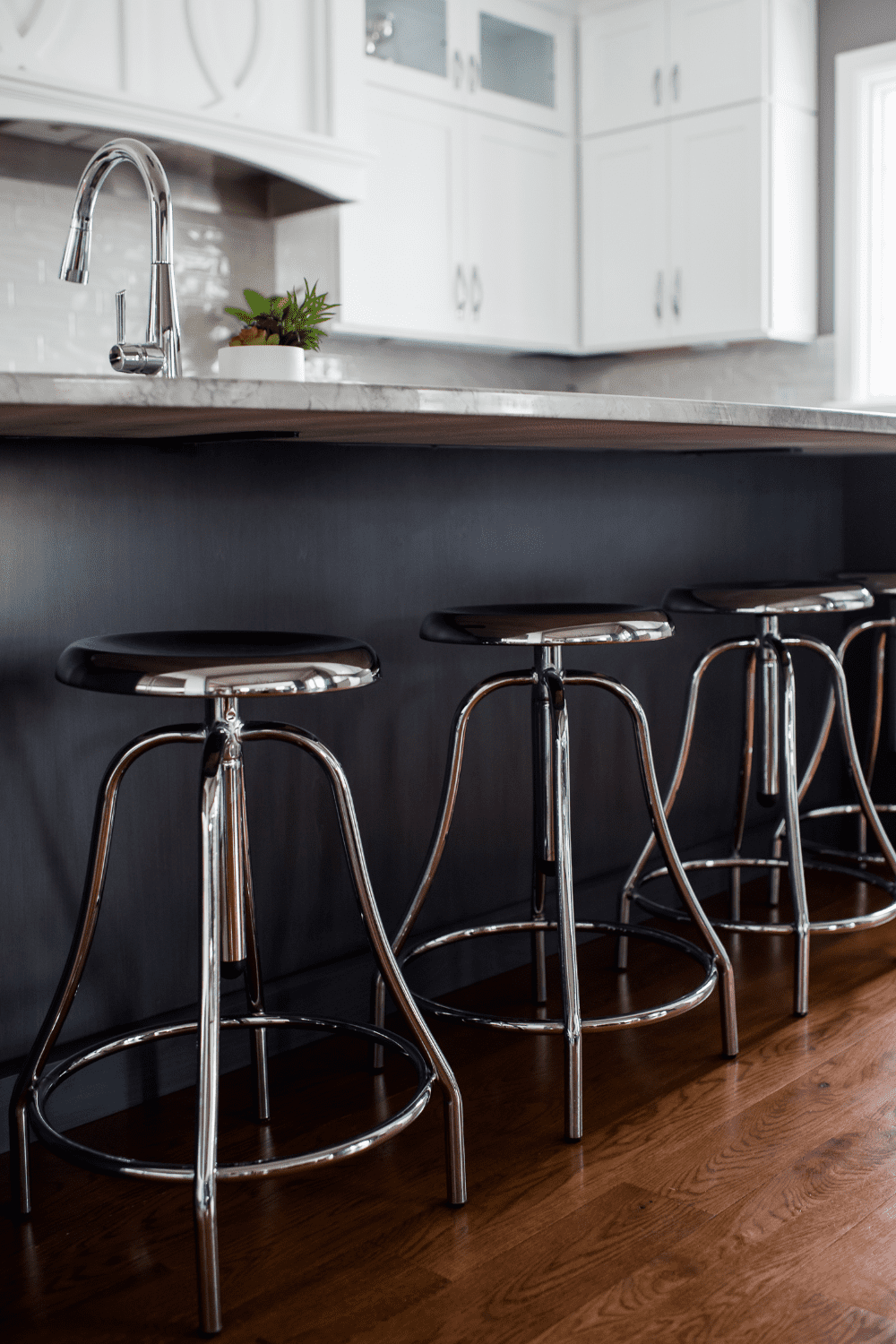 Nicholas Design Build | A kitchen with black counter tops and stainless steel stools.