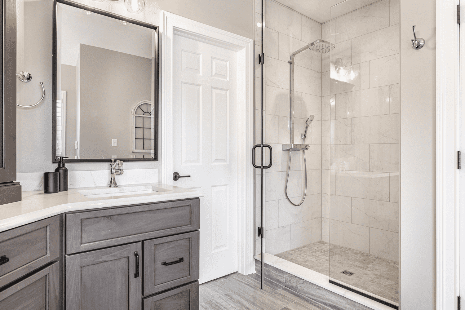Nicholas Design Build |         Description: A master bathroom remodel featuring gray cabinets and a shower stall.