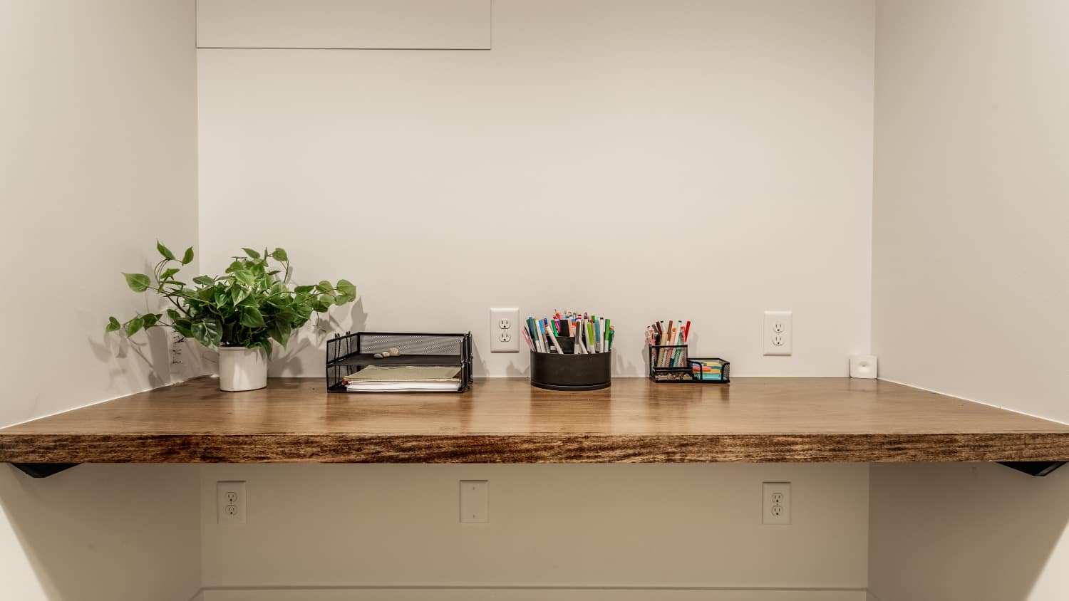 Nicholas Design Build | Remodel: A small office with a renovated wooden desk and a flourishing plant.