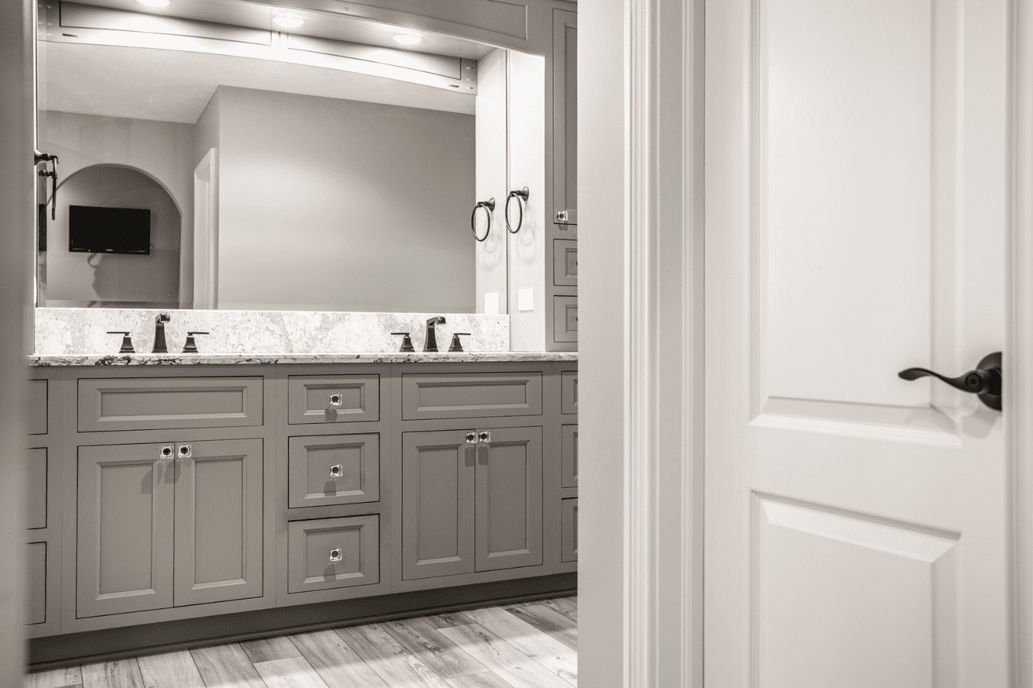 Nicholas Design Build | A bathroom with gray cabinets and a mirror.