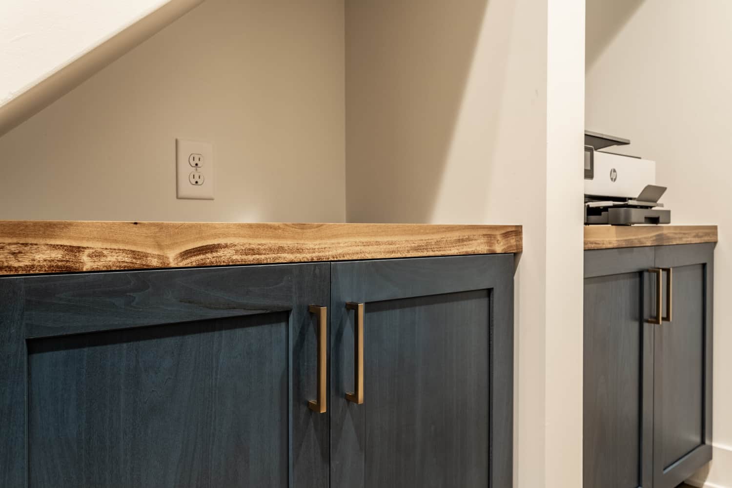 Nicholas Design Build | A remodeled blue cabinet under a staircase with a wooden top.
