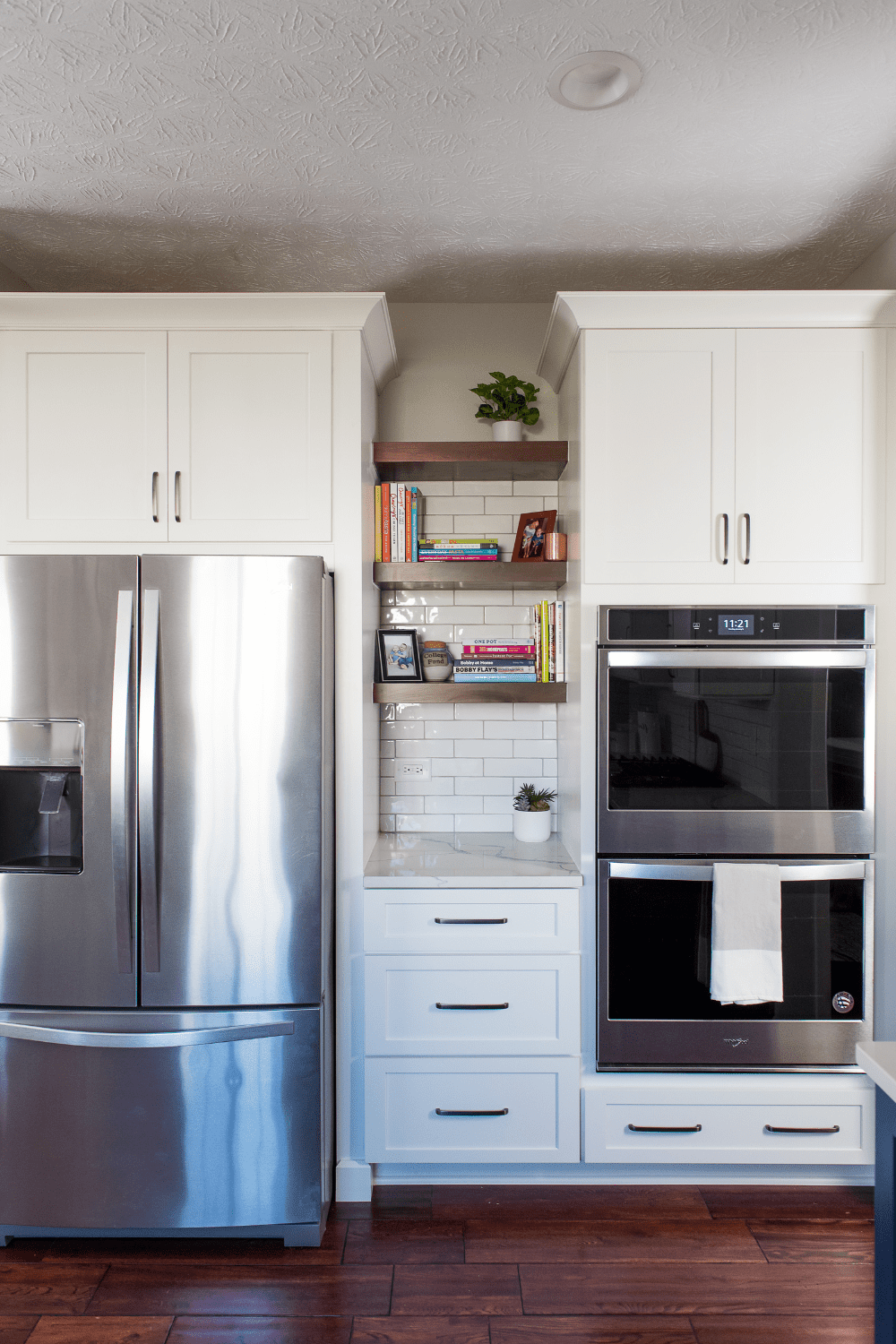 Nicholas Design Build | A white kitchen with a stainless steel refrigerator and oven.