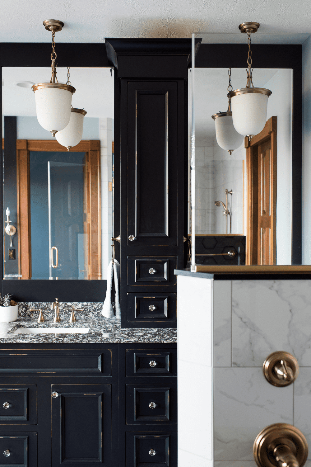 Nicholas Design Build | A bathroom with black cabinets and a mirror.
