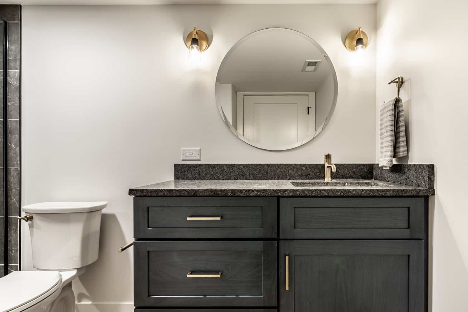 Nicholas Design Build | A black and gold bathroom remodel with a toilet and sink.