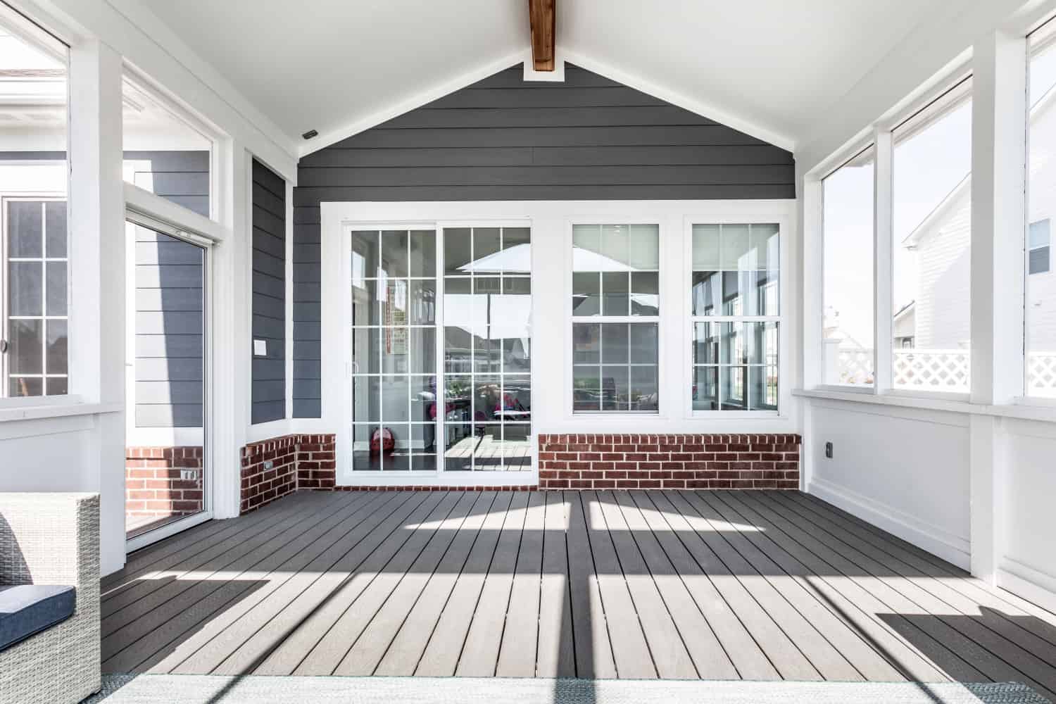 Nicholas Design Build | Remodel a screened in porch with gray walls and white furniture.
