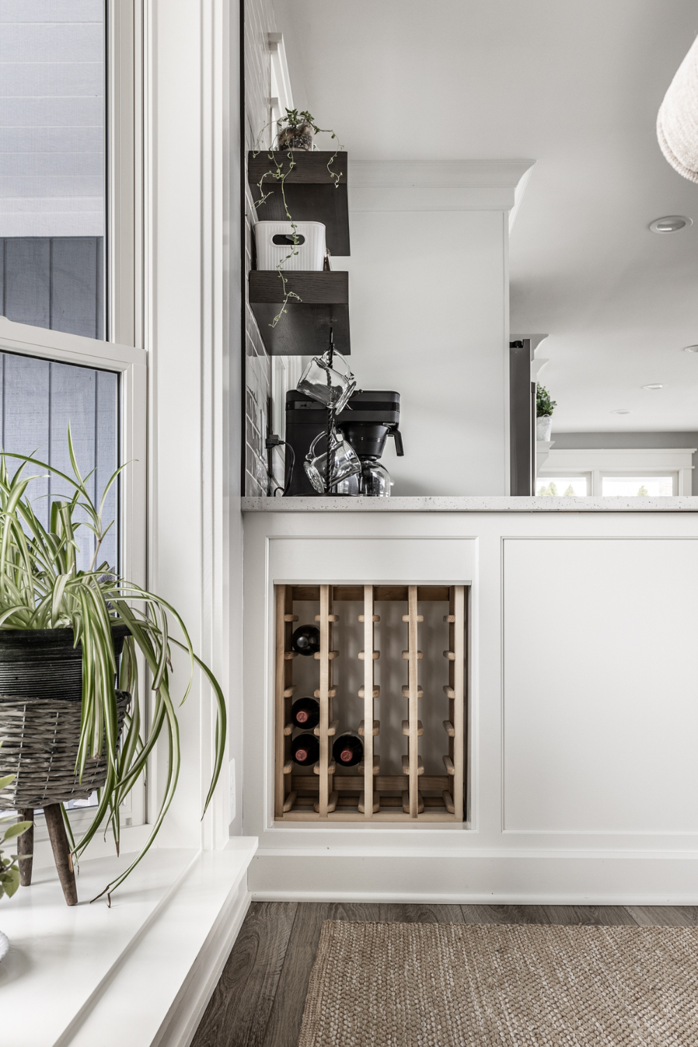 Nicholas Design Build | A white kitchen with a wine rack and a potted plant.