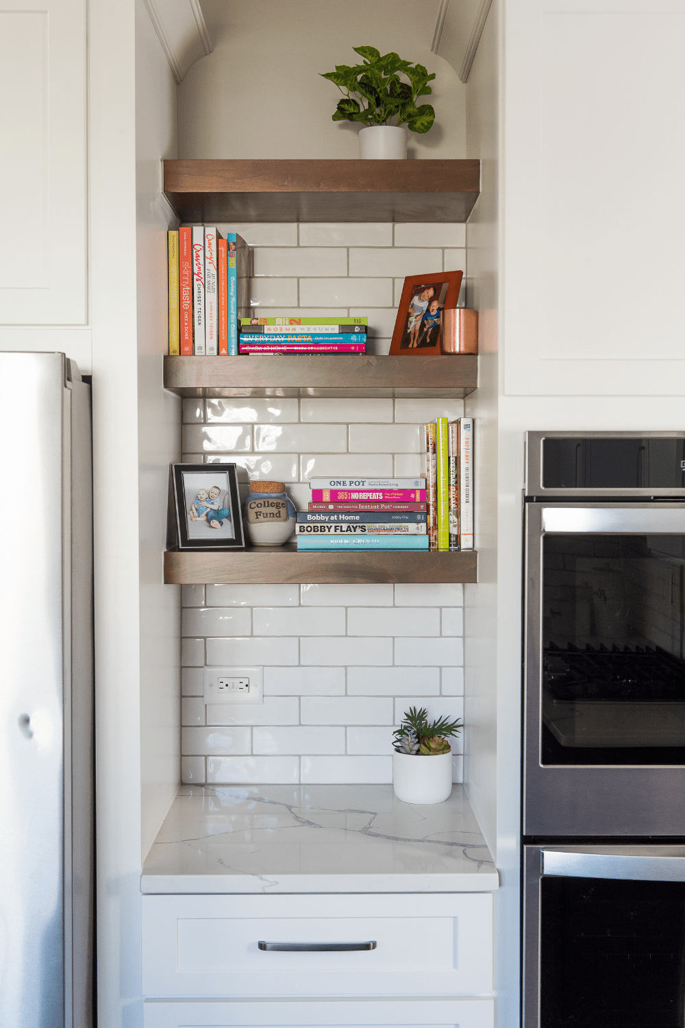 Nicholas Design Build | A white kitchen with bookshelves and a refrigerator.