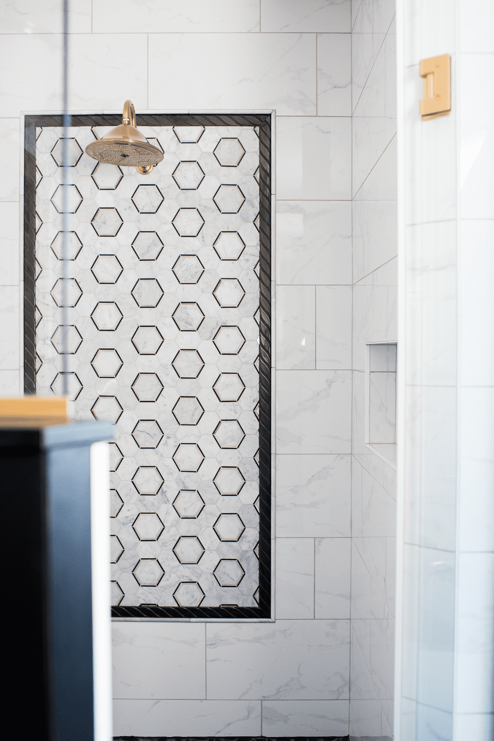 Nicholas Design Build | A bathroom with a black and white tiled shower.