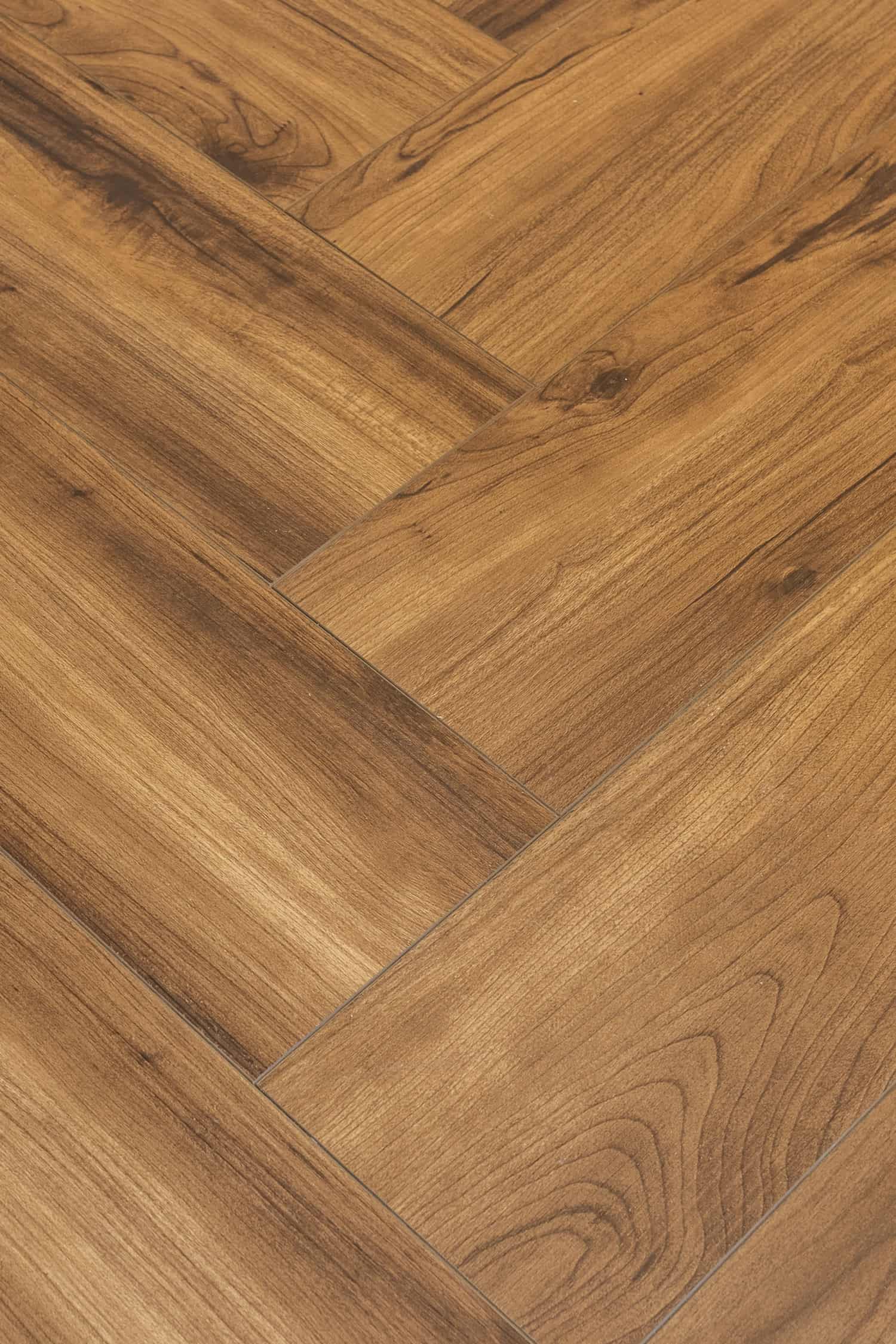Nicholas Design Build | A close up view of a wooden floor with a herringbone pattern, perfect for a bathroom design incorporating black and blue elements.