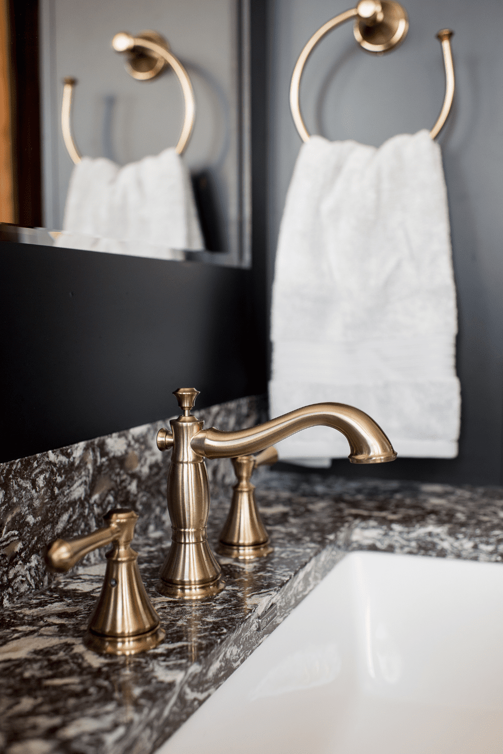 Nicholas Design Build | A bathroom with a marble counter top and brass faucet.