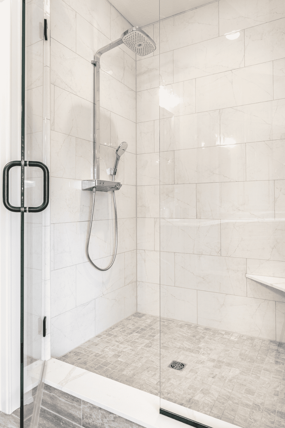 Nicholas Design Build | A master bath remodel with a white tiled shower and glass door.