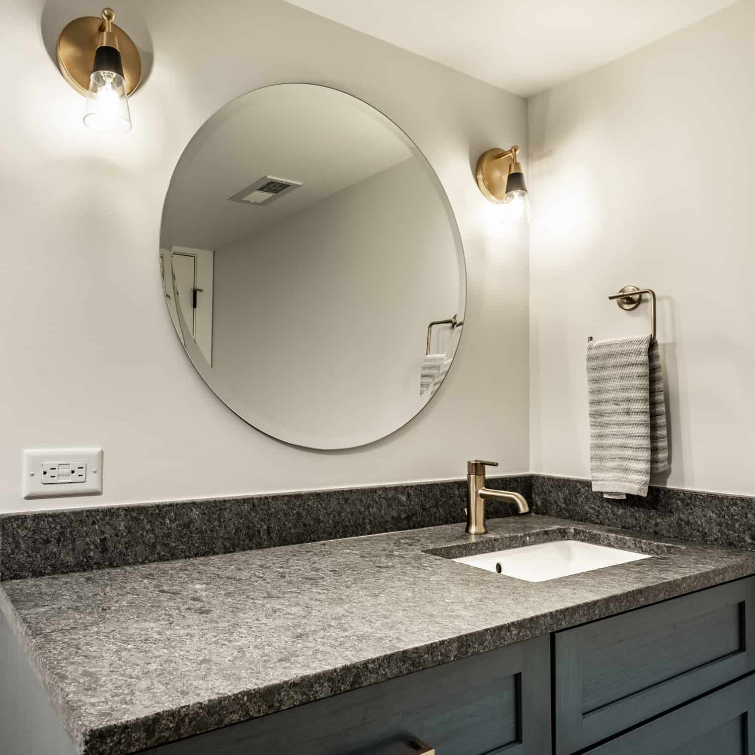 Nicholas Design Build | Remodel a bathroom with blue cabinets and a round mirror.