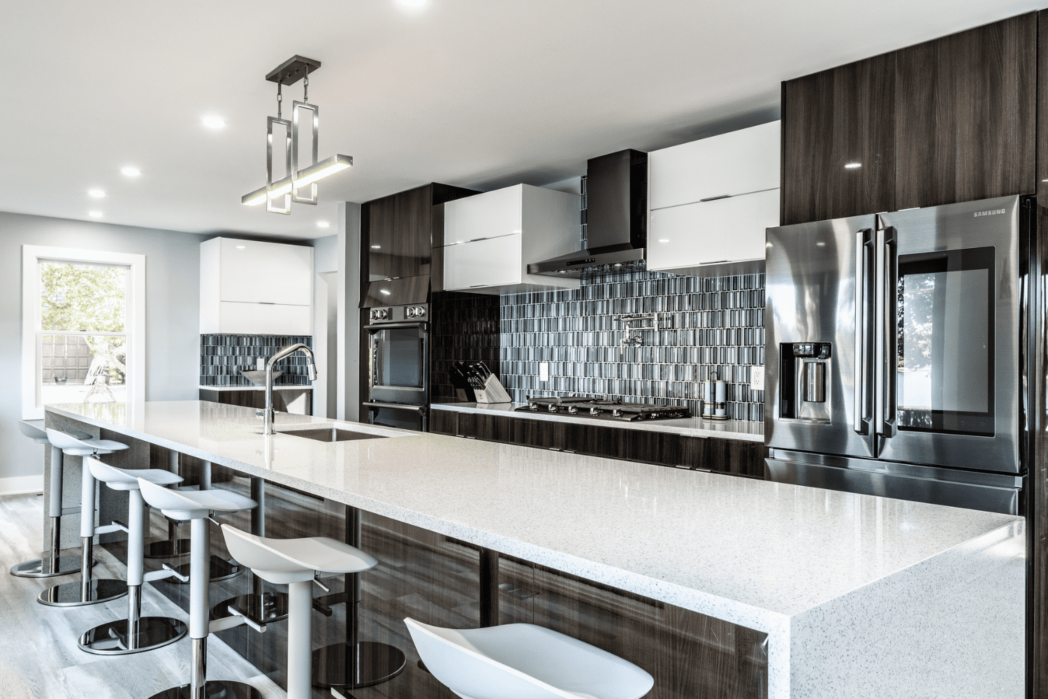 Nicholas Design Build | A modern kitchen with stainless steel appliances and bar stools.