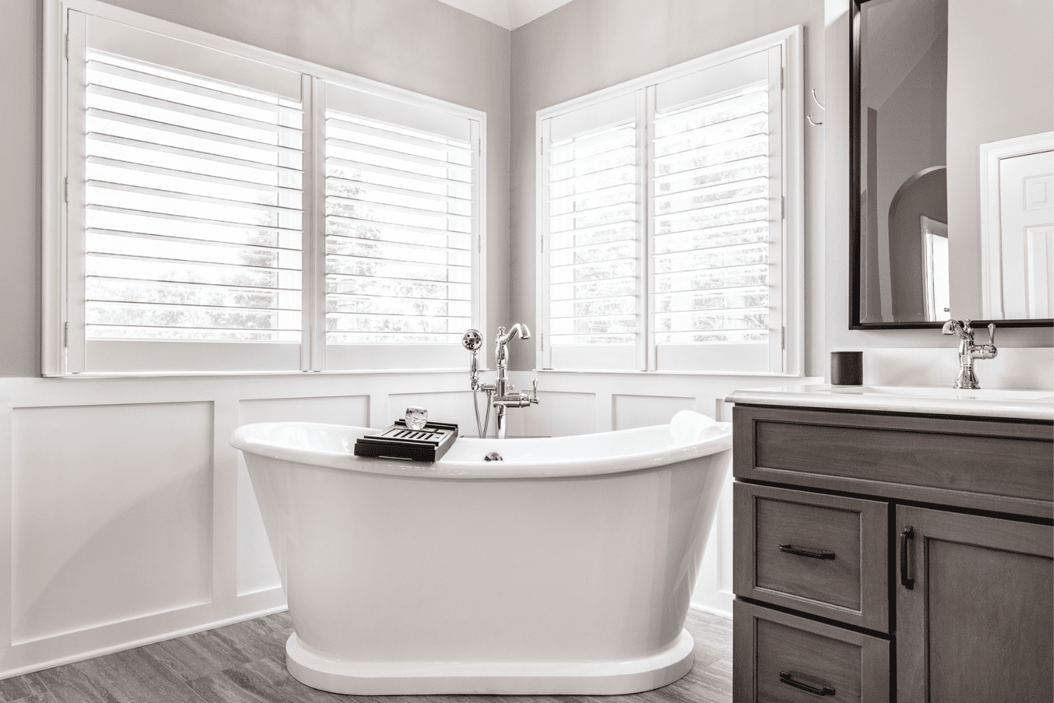 Nicholas Design Build | A master bath remodel featuring a white bathroom with wooden floors and white shutters.