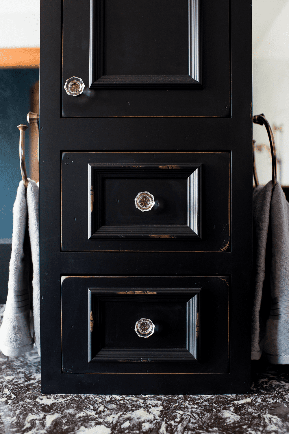 Nicholas Design Build | A black bathroom cabinet with two drawers and a towel rack.