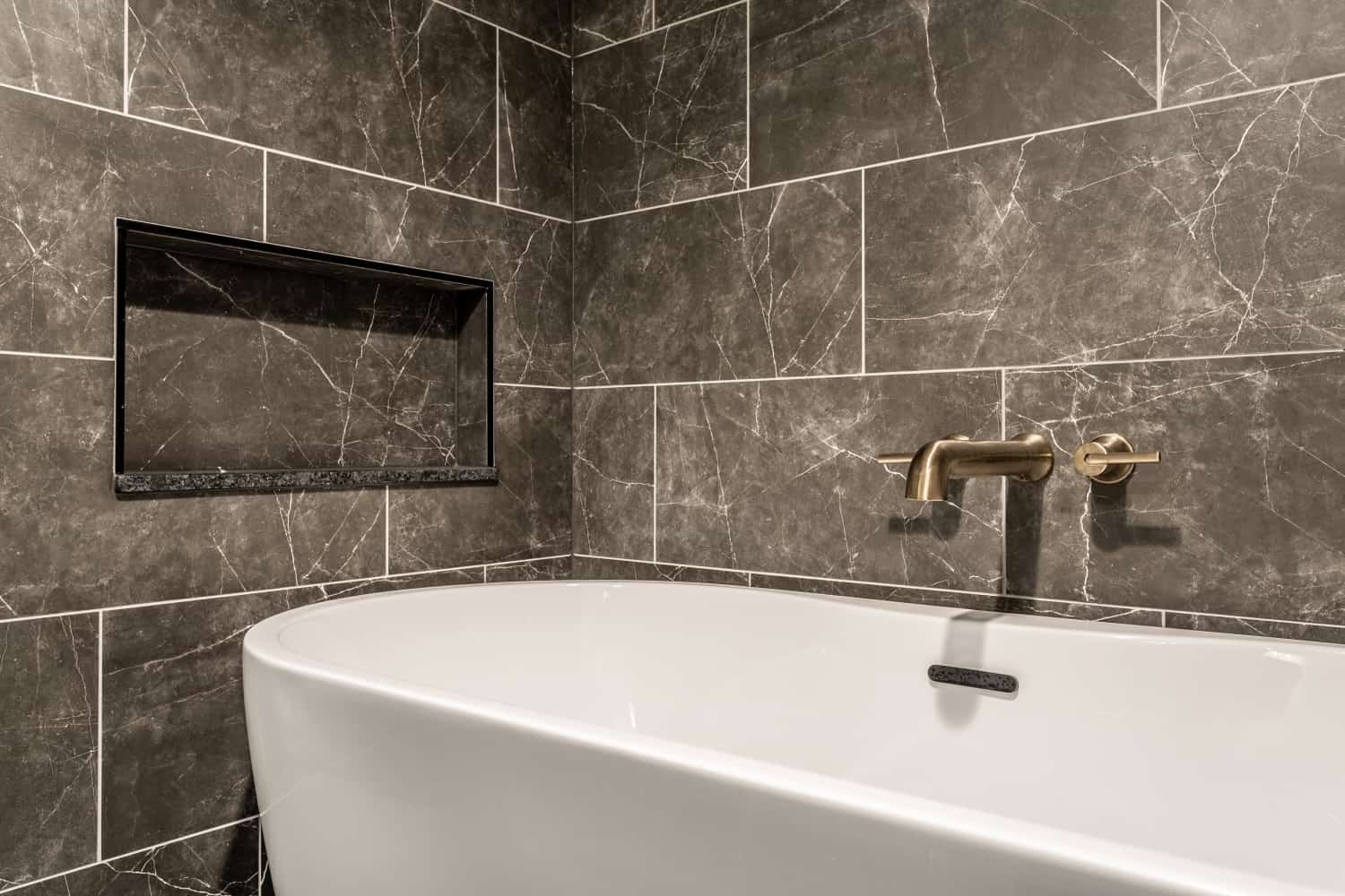 Nicholas Design Build | Remodeled bathroom with tiled walls and a bathtub.