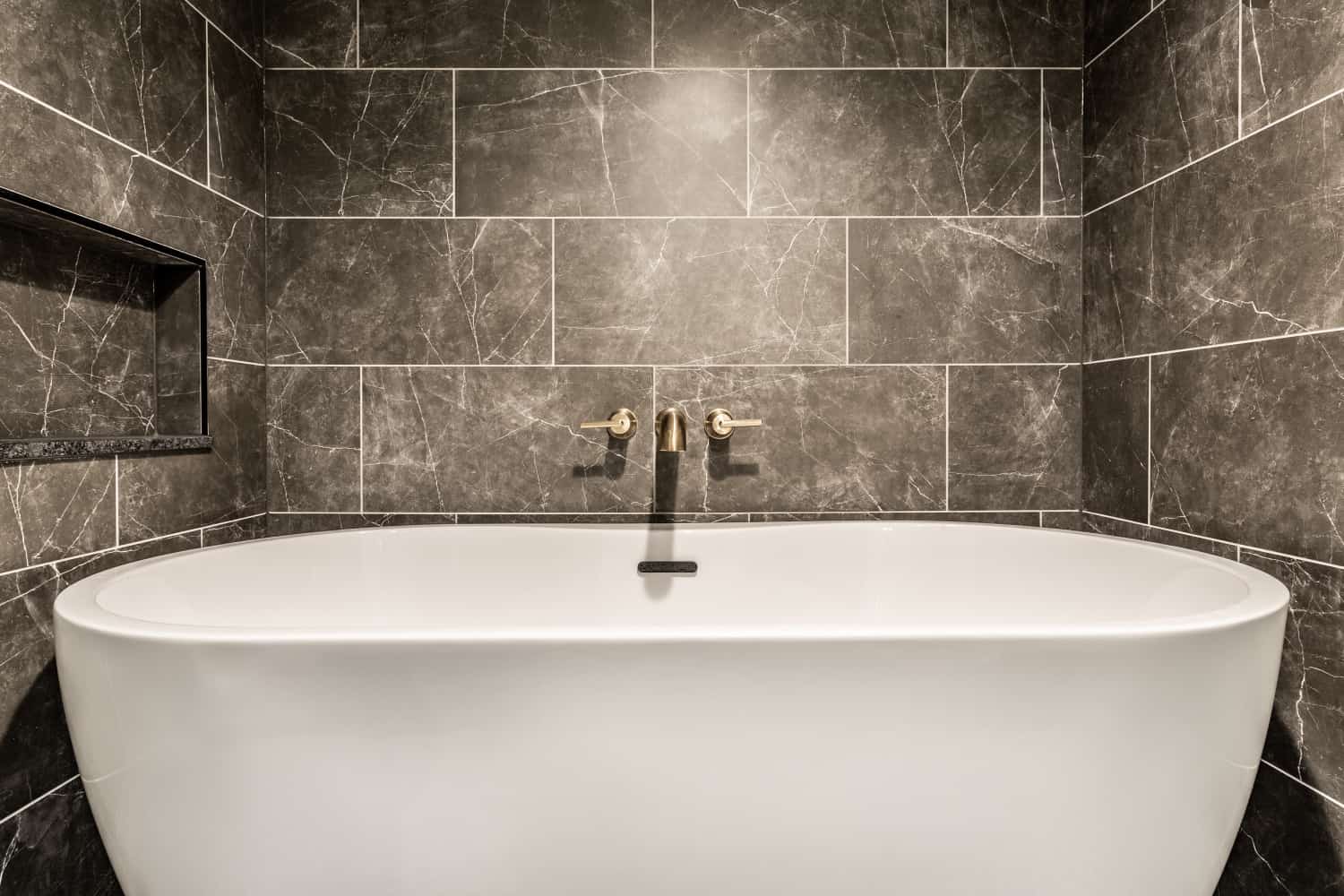 Nicholas Design Build | Remodel: A remodeled bathroom featuring a white bathtub and tiled walls.