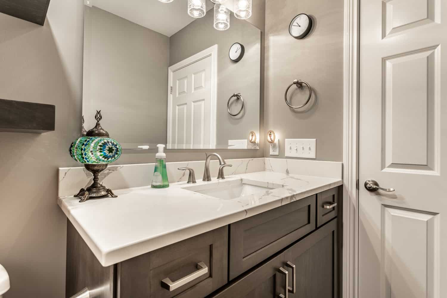 Nicholas Design Build | A remodeled bathroom with gray cabinets and a mirror.