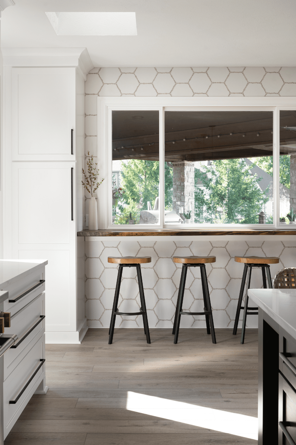 Nicholas Design Build | An image of a kitchen with white cabinets and stools.