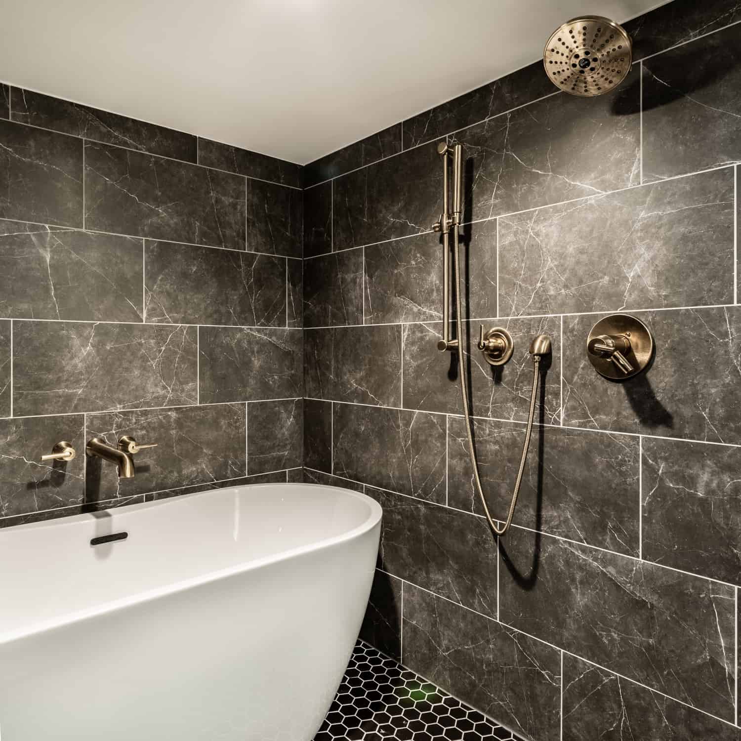 Nicholas Design Build | A remodeled bathroom with black tile and a bathtub.